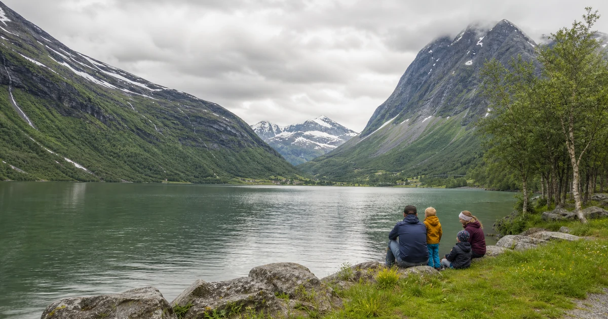 En familie ved grønt fjordvann mellom bratte fjell i Stryn og Loen